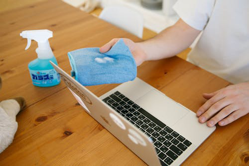 a person cleaning a laptop screen