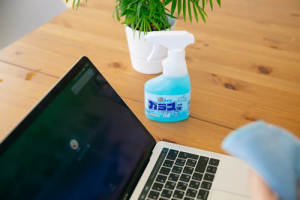 a person cleaning a laptop screen with a cloth