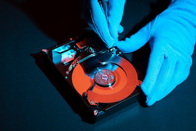 a person wearing gloves while handling a hard drive