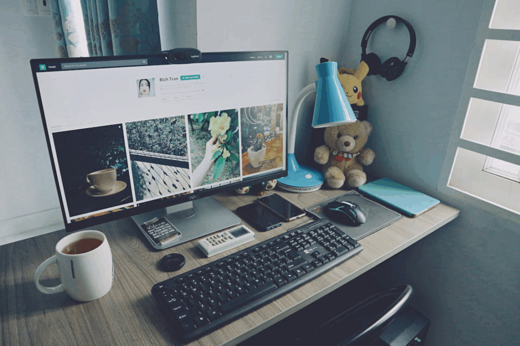 Desktop PC on a workstation with mug, lamp, and soft toys