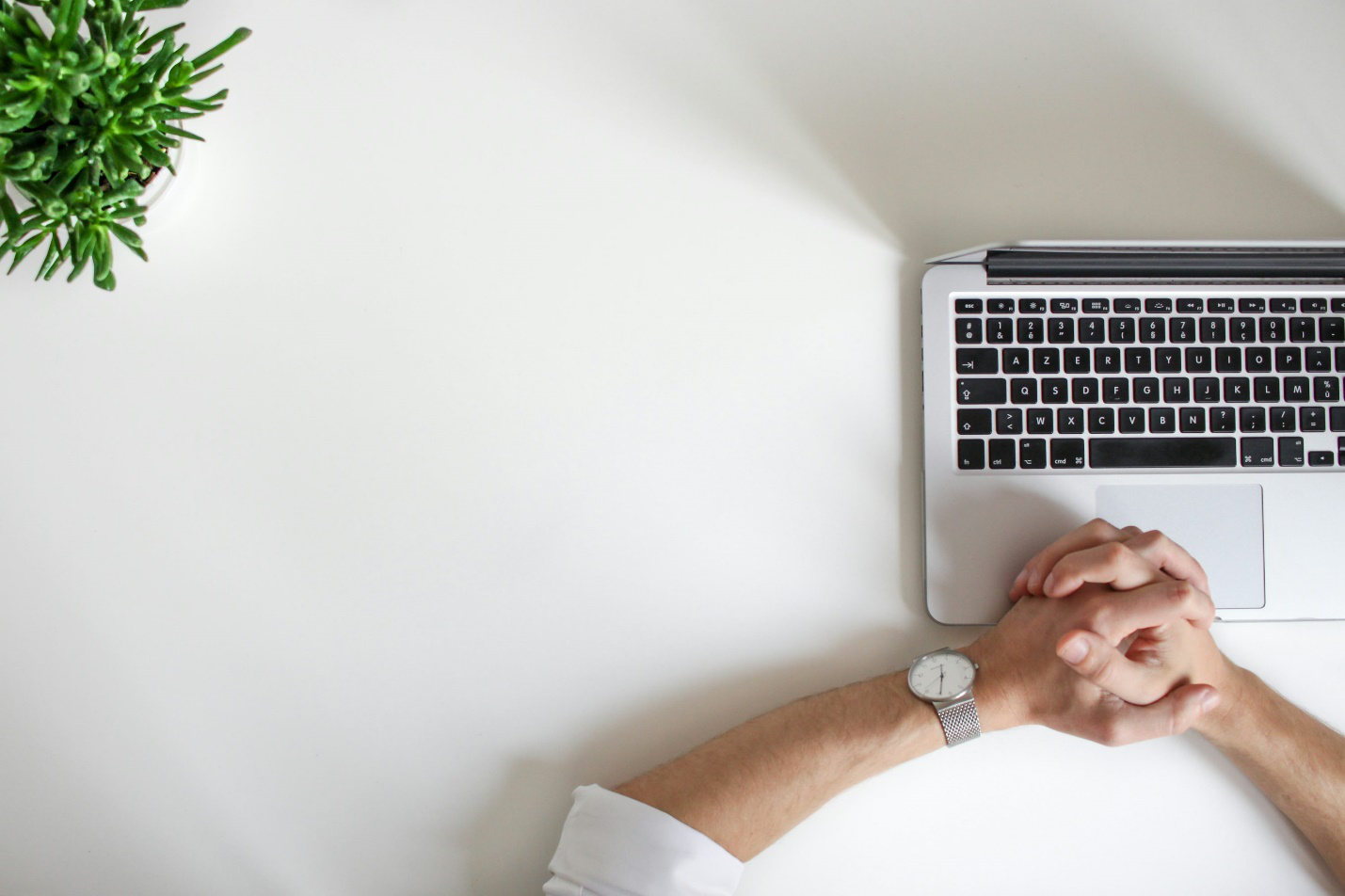 A person working on their computer on a white table.